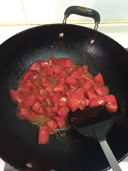 懒人版晚餐的做法操作步骤第6步：不用洗锅直接放入西红柿块熬酱，这里转为小火，用铲子把块状的西红柿压成糊状。