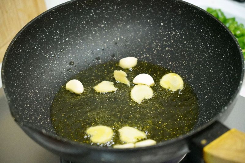 双椒炒鸡的做法操作步骤第7步：倒入姜蒜用金龙鱼外婆乡小榨菜籽油充分炸香