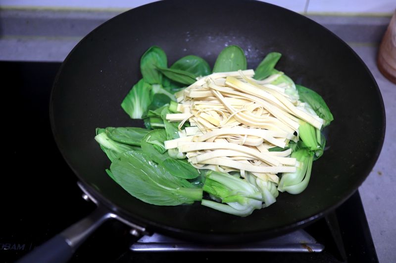鸡腿焖饭香喷的做法操作步骤第17步：炒锅中倒少许油，葱花炝锅，将油菜和豆腐丝同入锅；