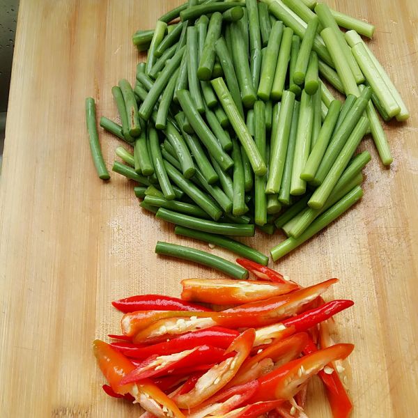五花肉炒蒜苔的做法操作步骤第2步：蒜苔切段，红椒切滚刀块。