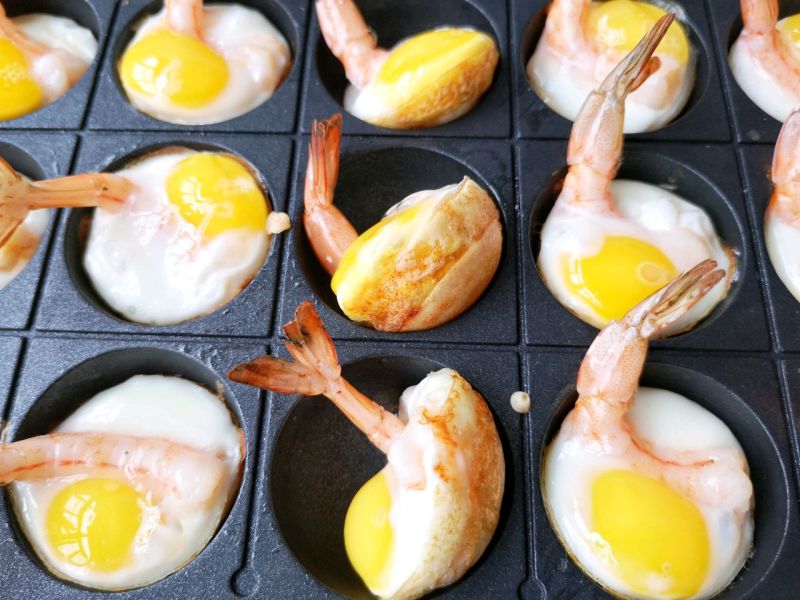 虾扯蛋的做法操作步骤第12步：待表面蛋液凝固，用叉子推起香脆的面糊加上鹌鹑蛋和鲜虾做出来的小半球，看到底部金黄焦脆。