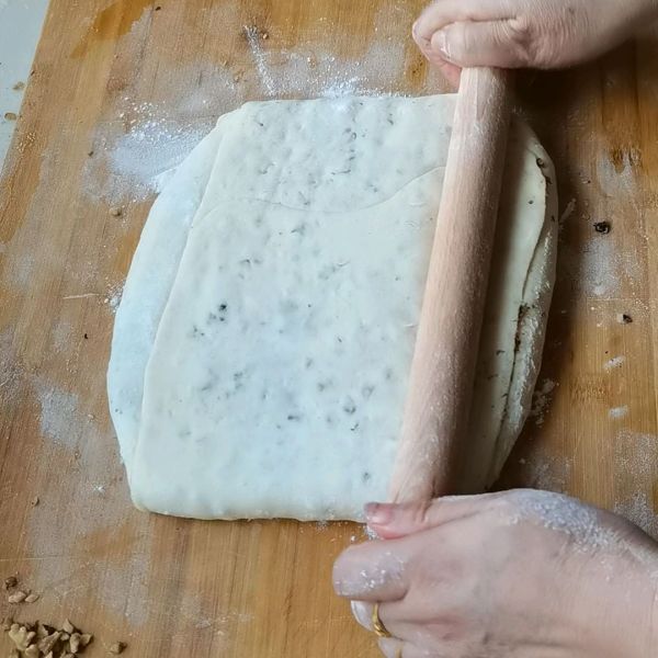核桃千层饼的做法操作步骤第10步：叠好的面团用擀面杖压一下喷水撒上芝麻