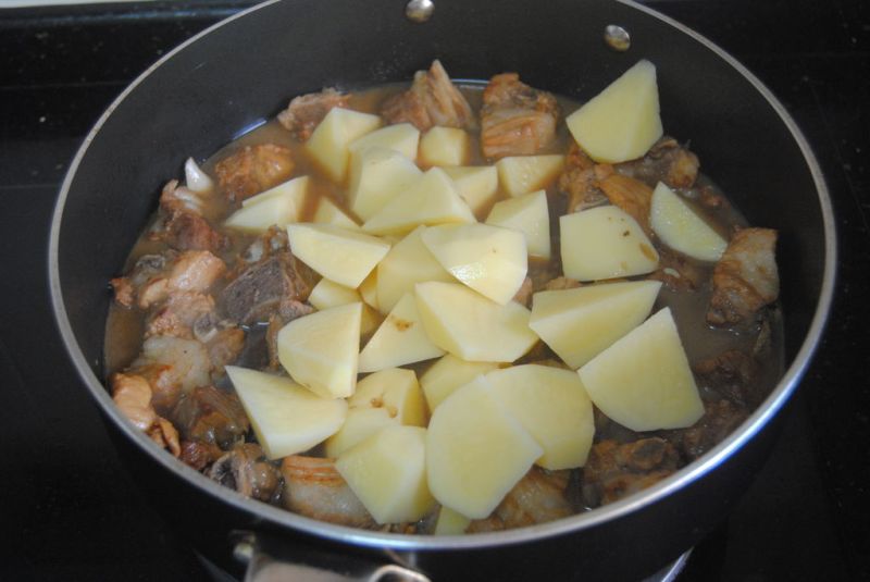 土豆烧排骨的做法操作步骤第9步：开盖子放入土豆翻炒均匀，再盖上盖子焖煮10-15分钟即可