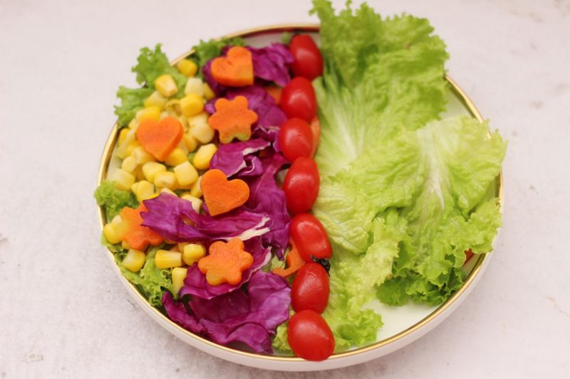 沙拉的做法操作步骤第8步：取一个大一点的盘子，盘子底下先铺上洗净的蔬菜，分别把玉米粒和紫甘蓝，胡萝卜和番茄摆盘。