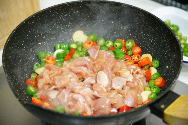 双椒炒鸡的做法操作步骤第9步：倒入腌制后的鸡肉加盐和黑胡椒大火翻炒，