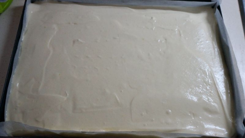 奶油戚风蛋糕卷的做法操作步骤第10步：蛋糕糊倒入铺好油纸的烤盘中，表面用刮板抹平，轻震两下，震出大气泡，入预热好的烤箱，中层，180度，上下火，15分钟左右，表面金黄