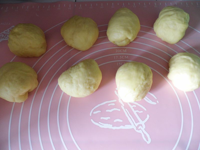 椰蓉面包的做法操作步骤第7步：然后把面团取出，分成八份（每个面团大约重60克），再滚圆，盖上保鲜膜松弛15分钟