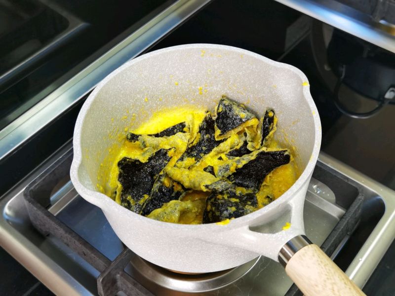 咸蛋黄海苔脆的做法操作步骤第9步：加入海苔脆，让咸蛋黄均匀包裹外表，撒些黑椒粒，抖匀。