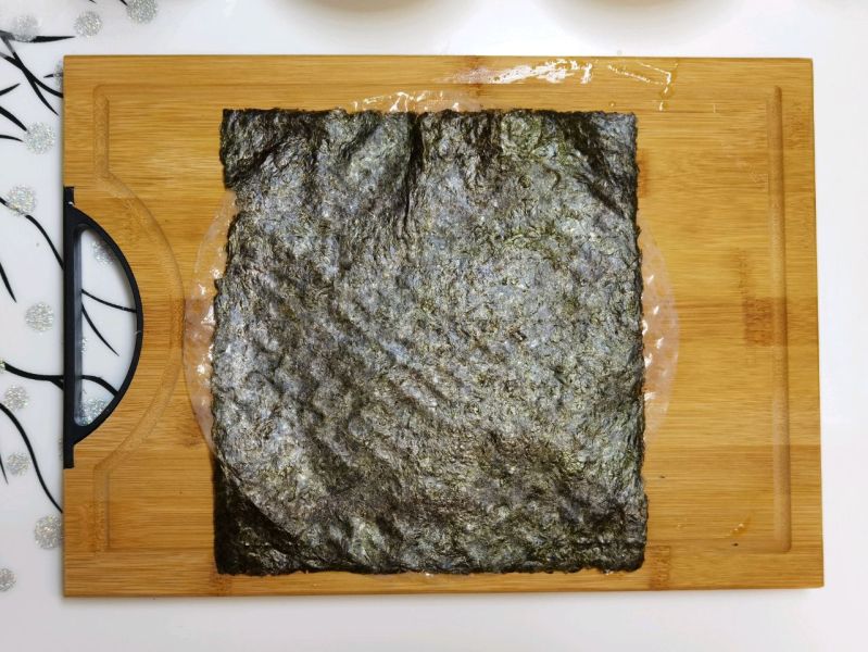 咸蛋黄海苔脆的做法操作步骤第4步：贴上一张海苔片，剪去四过多出的春卷皮，不剪也可以的。