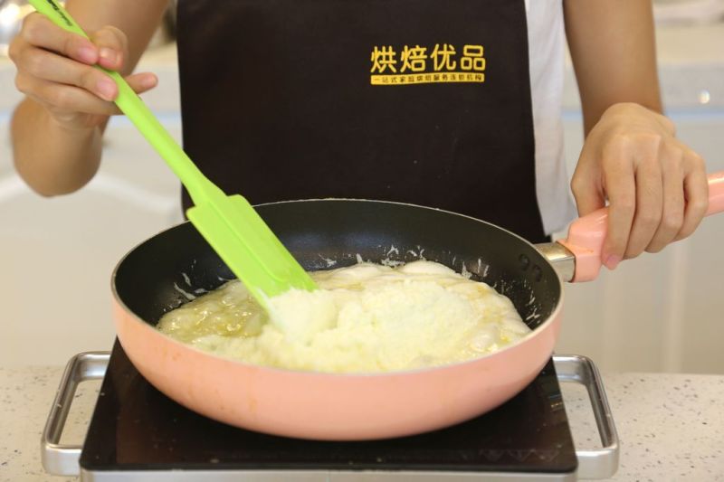 花生牛轧糖的做法操作步骤第4步：倒入奶粉，混合成奶糖糊