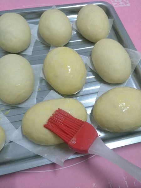 黄油面包的做法操作步骤第7步：放入烤盘里，发酵两倍大，刷上一层蛋液。
