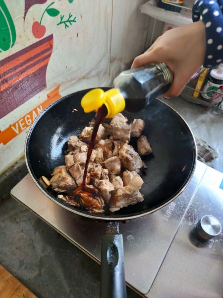 家庭铁锅炖的做法操作步骤第3步：加入排骨爆炒，炒至焦黄时依次加入生抽、老抽、鸡精、十三香，翻炒均匀