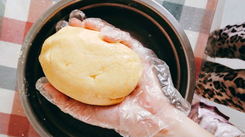 苹果派的做法操作步骤第4步：加入一颗蛋黄和水，揉成光滑面团，如图即可，保鲜膜包好放冰箱冷藏50分钟松弛