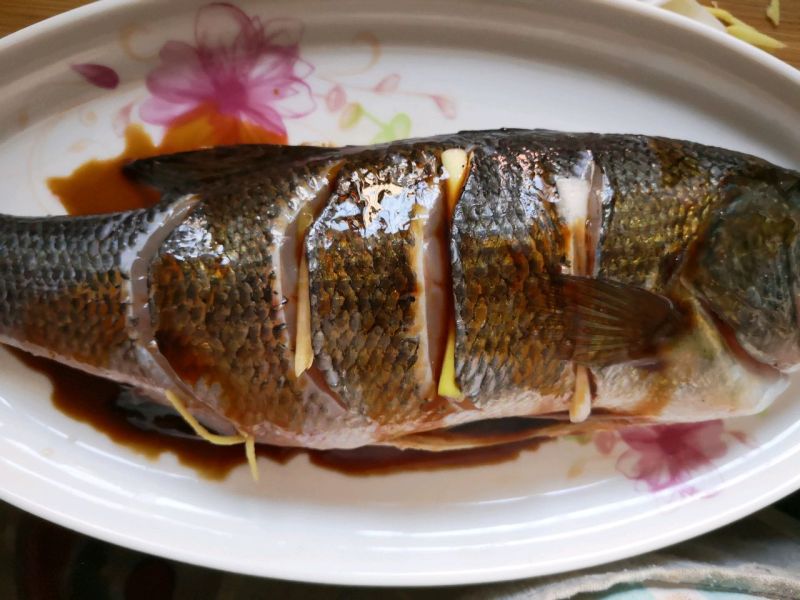 清蒸鲈鱼的做法操作步骤第5步：腌制好的鱼放入鱼盘内，浇上汁儿