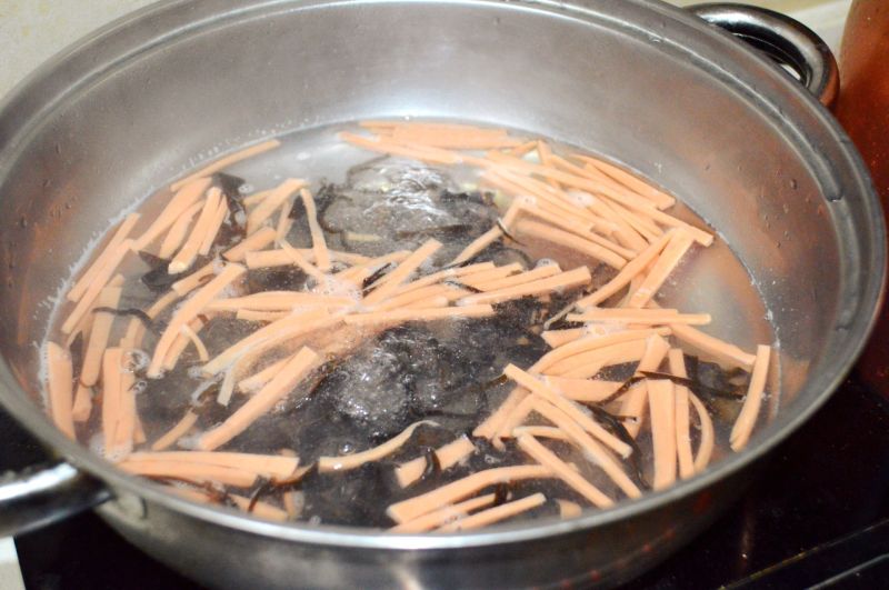 酸辣汤的做法操作步骤第6步：锅里放水，水开后放入木耳丝和火腿丝煮开。