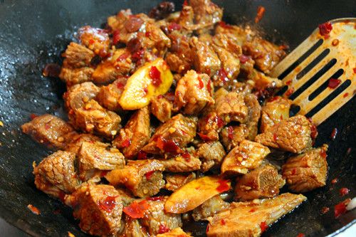 牛肉火锅的做法操作步骤第5步：将焯好的牛肉放入锅内煸炒，然后加入糖、味极鲜酱油煸炒匀均。