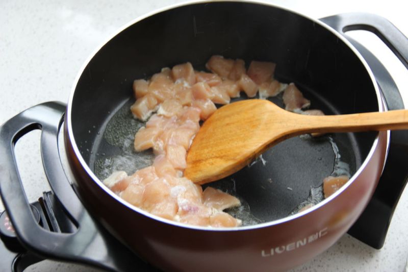咖喱鸡肉饭的做法操作步骤第5步：油温上来后，转中火加入腌制好的鸡肉，翻炒至变色。