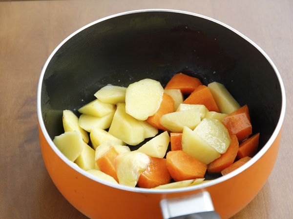 土豆咖喱饭的做法操作步骤第2步：煮锅倒入油，中火，胡萝卜和土豆倒入翻炒至土豆的切面有一半变白