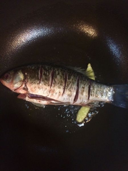 红烧鲫鱼的做法操作步骤第4步：锅内倒入比炒菜多一点的油，油热后先放两片姜下去炸一下（有效防止粘锅）
