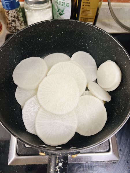 香菇萝卜煲的做法操作步骤第3步：锅里刷油，爆香姜片，倒入萝卜片中火翻炒。
⚠️ 炒个1-2分钟就可以，半透明状态。