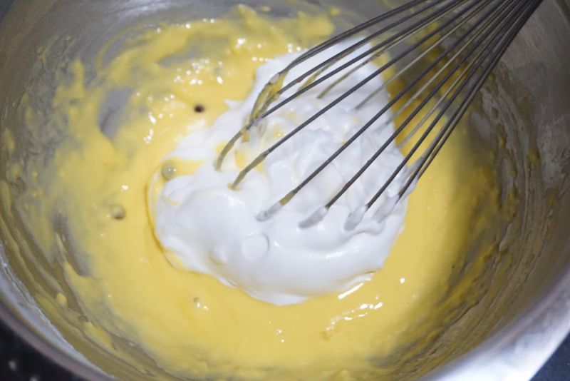 舒芙蕾松饼的做法操作步骤第5步：我们像做戚风蛋糕一样，将蛋白的一部分放入蛋黄糊中，用蛋抽或者刮刀结合，不要搅拌消泡，切拌的方法拌匀。