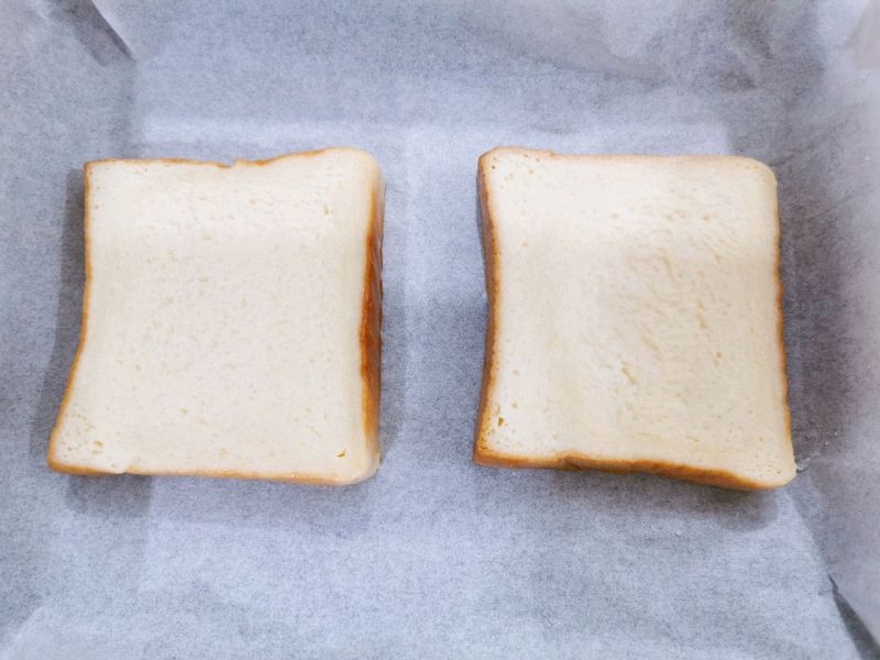 奶香爆浆三明治的做法操作步骤第6步：烤盘铺上硅油纸，没有蘸蛋奶液的一面靠硅油纸