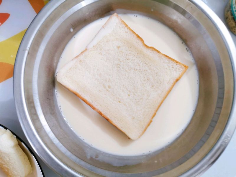 奶香爆浆三明治的做法操作步骤第5步：取两片吐司，吐司的其中一面都蘸上蛋奶液