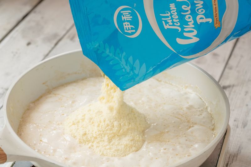 雪花酥的做法操作步骤第4步：倒入50g奶粉继续拌匀。