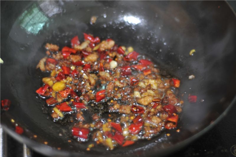 干煸四季豆的做法操作步骤第6步：加入料酒、生抽、蒜瓣、干红辣椒、葱、姜末，翻炒均匀