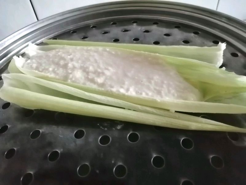 奶香玉米耙耙的做法操作步骤第6步：玉米叶清洗干净，铺在蒸笼上，将玉米糊倒入