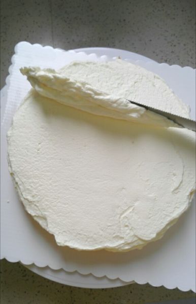 水果奶油裱花蛋糕的做法操作步骤第21步：先在底部的蛋糕片上抹奶油，奶油尽量抹匀，我没有蛋糕抹刀，就用一个长的切面包的刀没有齿的那面操作的