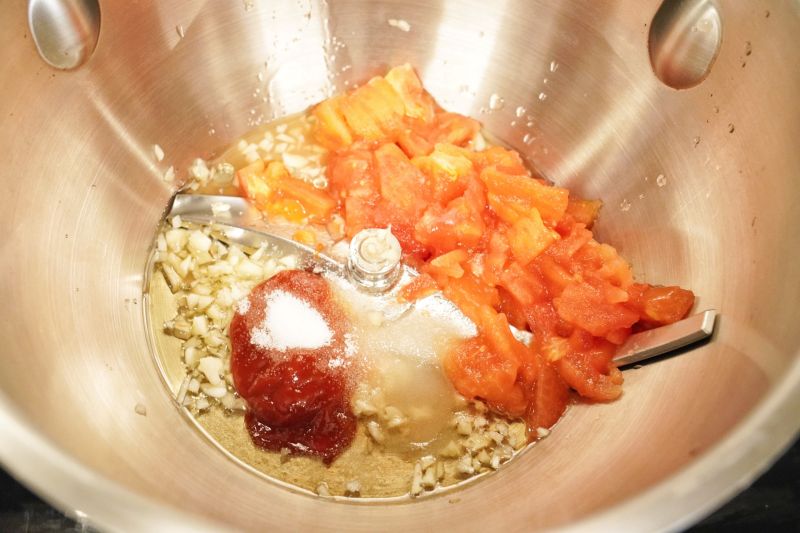 茄汁金针菇的做法操作步骤第8步：把蒜末、番茄酱、盐、白砂糖和西红柿碎放入烹饪锅里
