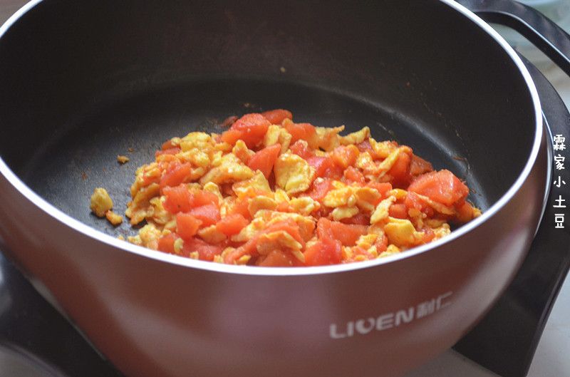 番茄鸡蛋拌面的做法操作步骤第10步：倒入之前炒好的鸡蛋碎，翻炒均匀，加盐拌匀，关闭电火锅电源。