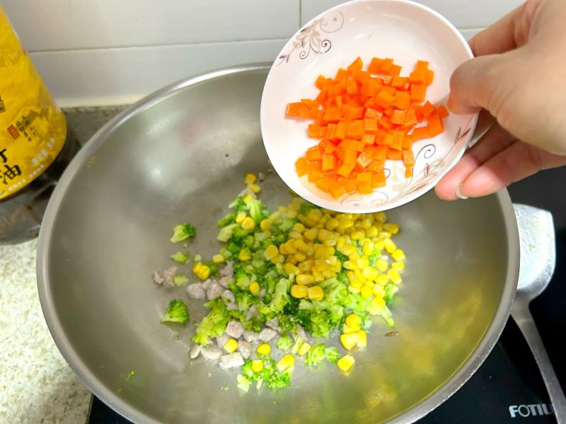 蛋炒饭的做法操作步骤第6步：倒入胡萝卜粒